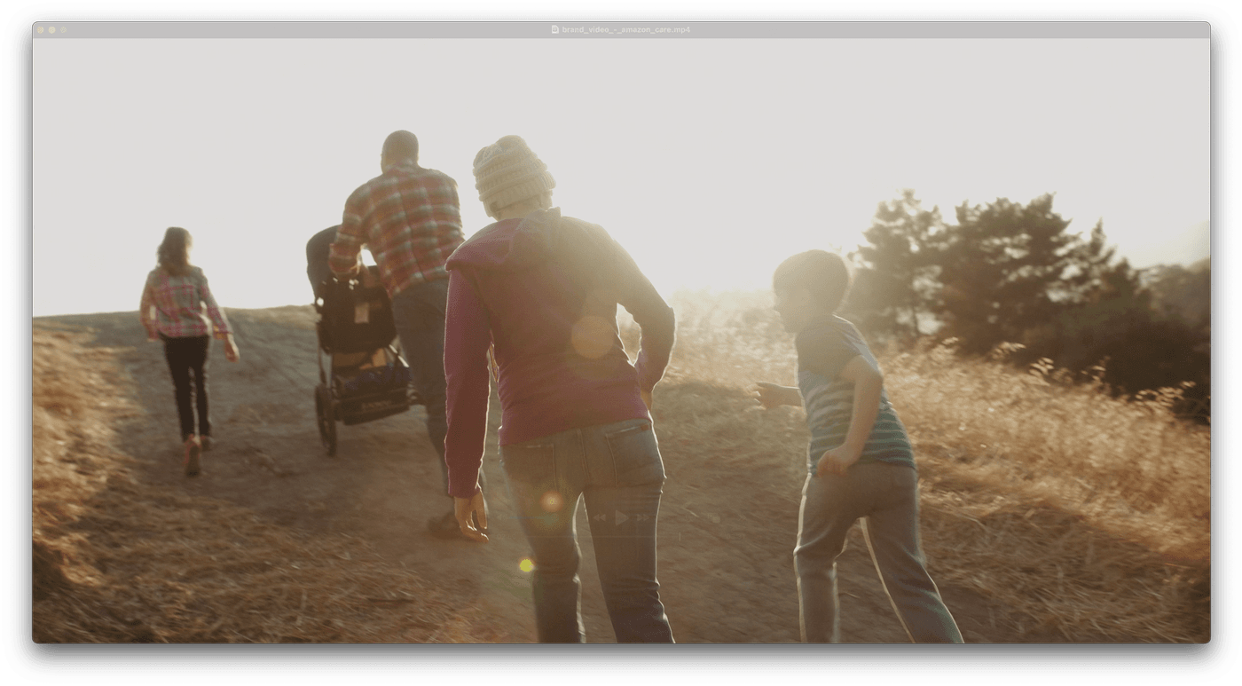 A family of five walks up a dirt path at sunset, with a parent pushing a stroller while another child runs ahead and a teenager walks in the distance.